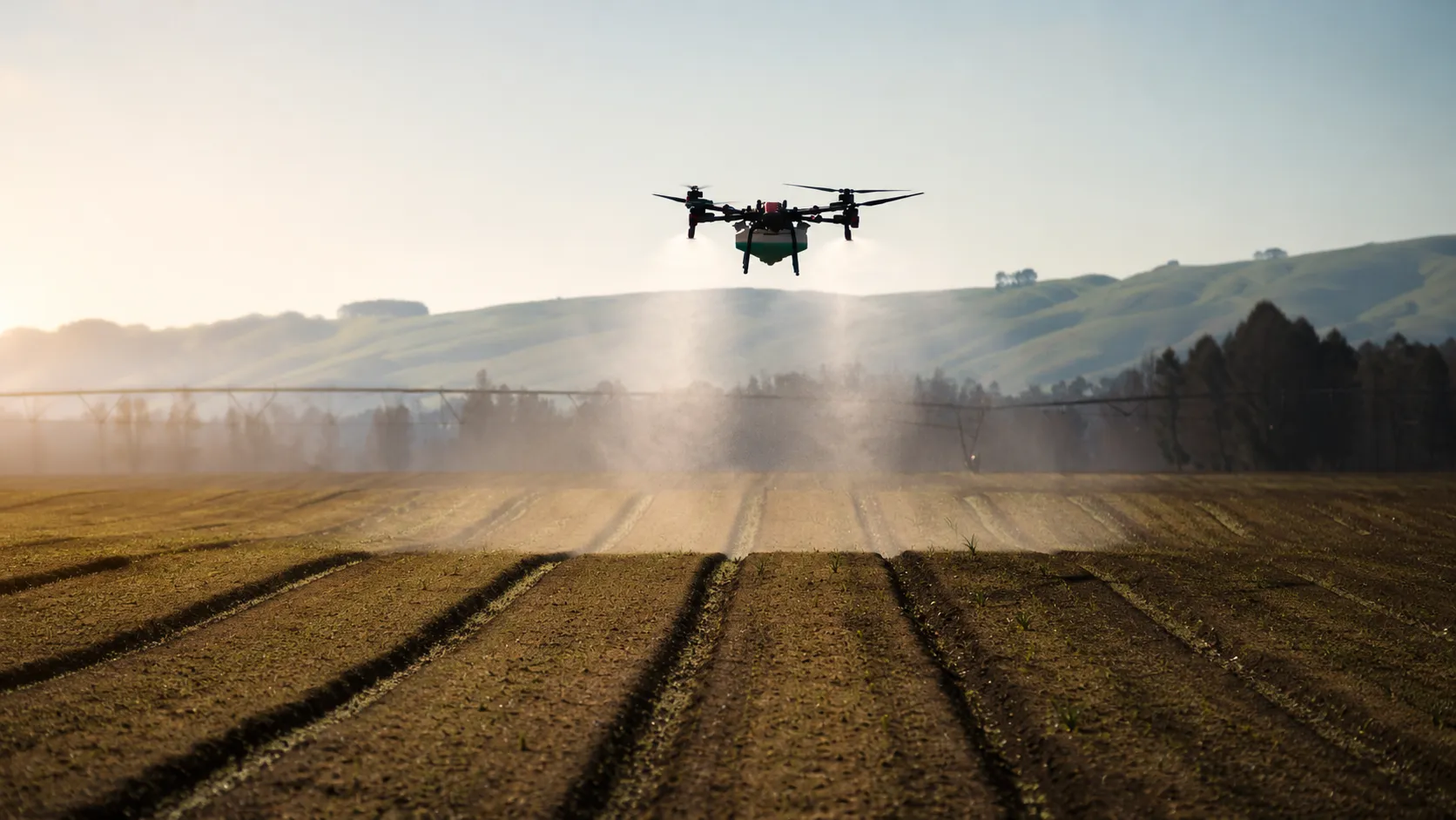 A Vantage spray drone applying product low over a cultivated field at sunrise