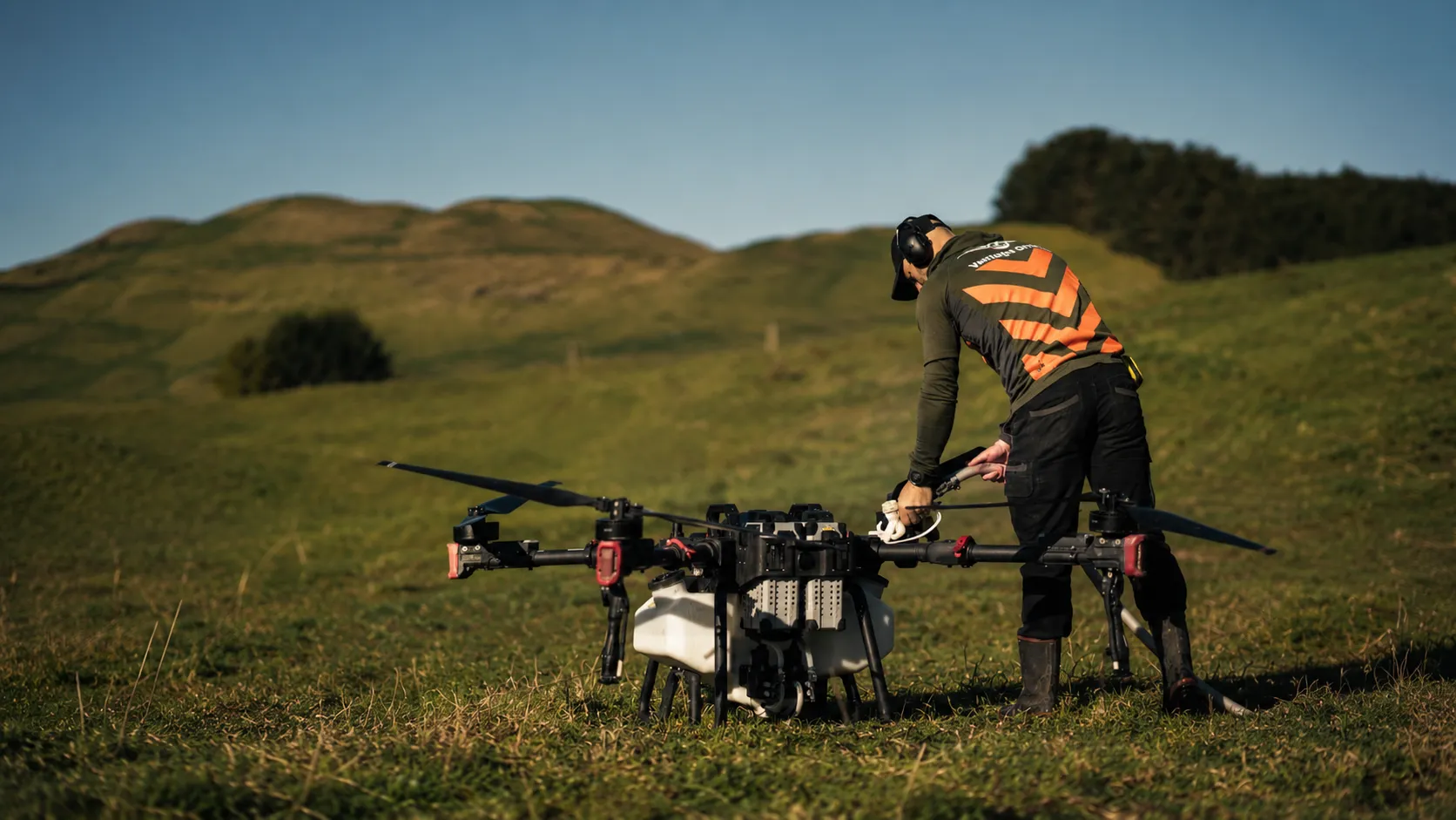 A Vantage Drone Services operator in hi-vis preparing a spray drone in a paddock
