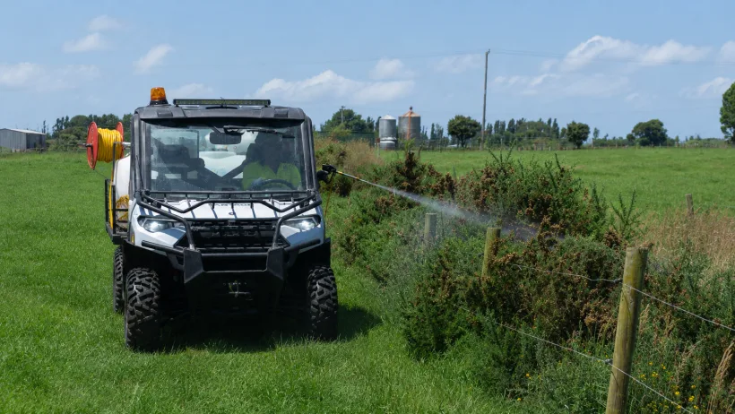 A Polaris ground rig spraying along a farm fence line