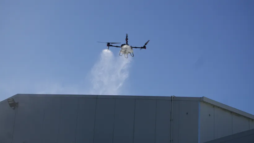 A drone applying moss and mould treatment across a commercial roof